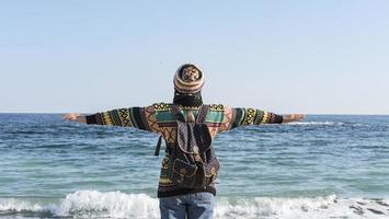 a girl in a colorful sweater and hat walk on the autumn sunny beach photo