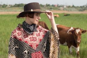 Young woman traveler in poncho and hat walk in the fields and farm