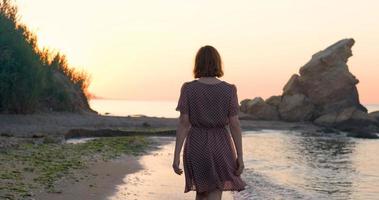 mujer joven vestida relajándose en la playa de verano durante el hermoso amanecer foto