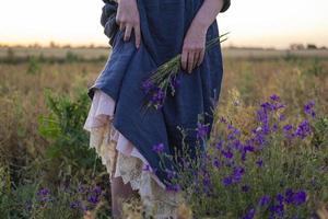 mujer joven pelirroja con pecas en vestido vintage hecho a mano caminar en campos con flores foto