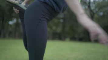 una joven mujer delgada con ropa deportiva estirando su cuerpo después de trotar por la mañana en el parque natural, cuidando la forma del cuerpo, estirando las piernas para la flexibilidad del cuerpo, la vida doméstica, las personas y el concepto de atención médica video