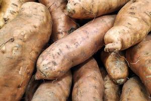 pila de batatas en un puesto de mercado foto