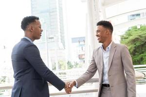 Welcome to our team. young modern men in smart casual wear shaking hands. Two smiling businessmen shaking hands together. Two confident businessmen shaking hands at the outside of the office. photo