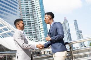 Welcome to our team. young modern men in smart casual wear shaking hands. Two smiling businessmen shaking hands together. Two confident businessmen shaking hands at the outside of the office. photo