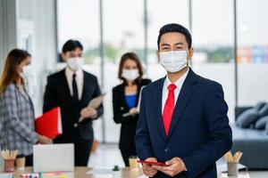 business man waering mask with holding tablet and people background photo