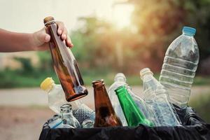 hand holding garbage bottle glass putting into recycle bag for cleaning photo