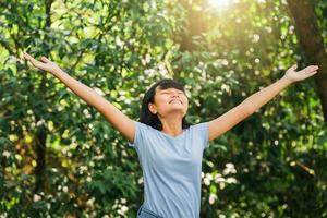 Smiling woman open arms while standing in forest photo