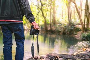 hombres viajeros con cámara en la mano caminan en la cascada foto