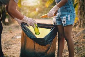 woman hand picking up garbage glass bottle for cleaning at park photo