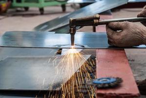 trabajador cortando chapa de acero con soplete de metal en la fábrica foto