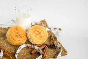 leche y pan con cinta métrica para dieta sobre fondo blanco foto