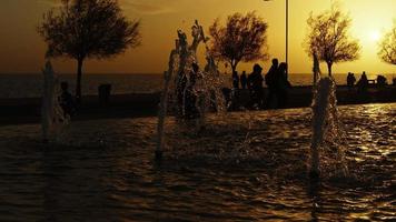 fontaine à eau et silhouette de personnes au coucher du soleil video