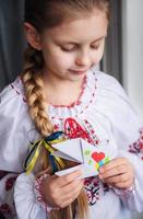 A little Ukrainian girl in traditional clothes holds a paper dove of peace in her hands photo