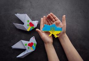 Hands holding the shape of Ukraine border with color flag photo