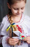 A little Ukrainian girl in traditional clothes holds a paper dove of peace in her hands photo