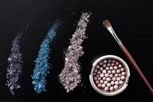 Makeup brush and cosmetics on black isolated background. Top view and mock up