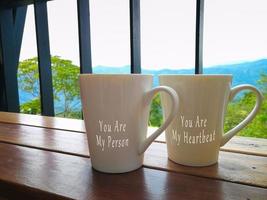 Text on two porcelain cups facing the mountain view photo