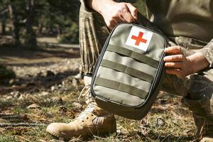 Military army first aid kit. Camouflaged soldier medic. photo