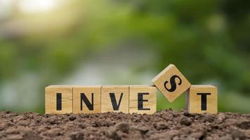bloque de madera en terrenos etiquetados invertir ideas de crecimiento financiero e inversiones en valores. foto
