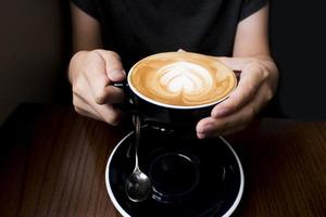 café con leche en la mano. fondo oscuro foto