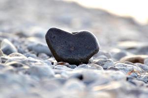 Heart shape stone against background of beach. Summer sunny day. Love, wedding and Valentine day concept. Finding beautiful and interesting stones. Beach vacation photo