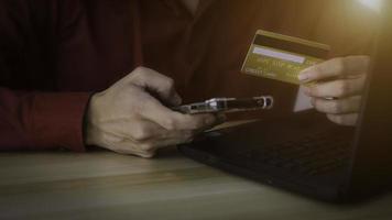 Close hands of men using credit cards and laptops, smartphones to shop online.