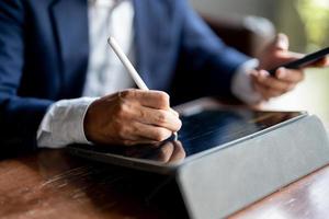 primer plano de la mano del hombre usando la pluma y la computadora portátil nota algo concepto comercial, planificación o inclinación. foto