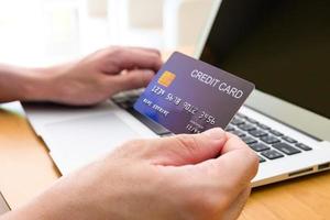 los hombres sostienen la tarjeta de crédito y escriben la información de pago en el teclado para ordenar compras en línea. tecnología de Internet y concepto de estilo de vida de comercio electrónico de mercado digital, transacción de compra. foto