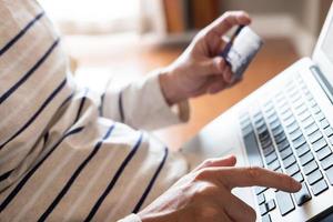 Selective focus at men hand pressing enter on keyboard. Close up shot at men while enter security key on credit card for online payment shopping. Wireless banking transaction via internet technology. photo