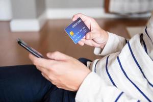 Selective focus at men hand holding mobile phone. Close up shot at men while enter security key on credit card for online payment shopping. Wireless banking transaction via internet technology. photo