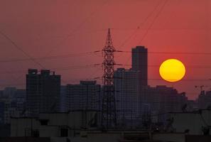 Sun setting behind tall skyscrapers over a skyline of Mumbai photo