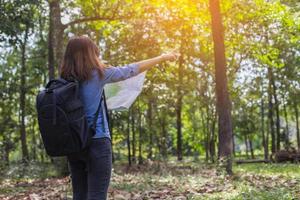 Women hiker with backpack checks map to find directions in wilderness area photo