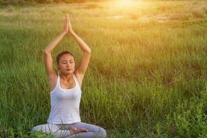 yoga en la ciudad hermosa mujer joven en forma usando ropa deportiva meditando, respirando, sentada con las piernas cruzadas en una postura de medio loto en la calle el día de verano, ardha padmasana, espacio de copia foto