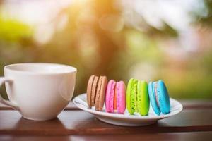 macarrones de san valentín con café en la mesa de madera. imagen tonificada foto