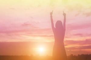 Silhouette of woman praying over beautiful sky background photo
