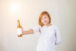 Una alegre y encantadora chica fitness con top rosa que muestra una botella de agua sobre fondo blanco. foto