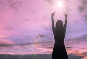 silueta de mujer rezando sobre un hermoso cielo de fondo foto