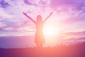 Silhouette of woman praying over beautiful sky background photo