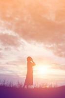 Silhouette of woman praying over beautiful sky background photo