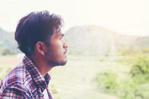 Hipster man smoking cigarette, standing behind a mountain. Among the fresh air in the morning. photo