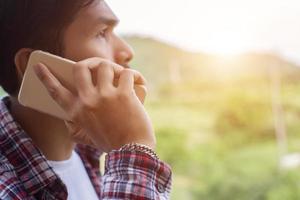 joven hipster barbudo hablando por teléfono, sonriendo, fuera de la vista a la montaña. foto