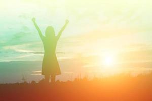 Silhouette of woman praying over beautiful sky background photo