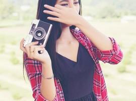 joven fotógrafa hipster sosteniendo una cámara vintage. foto