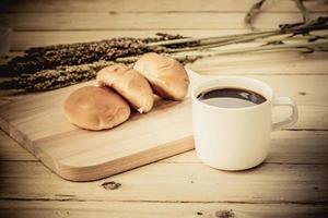 Coffee cup and bread on wooden floor photo