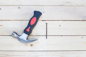 Hammer and rusty nail on white wooden background photo