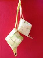 ketupat, una cultura culinaria originaria de indonesia, generalmente se vende en el mercado antes de las celebraciones de eid al-fitr. ketupat con fondo rojo. concepto de diseño. ilustración de diseño foto