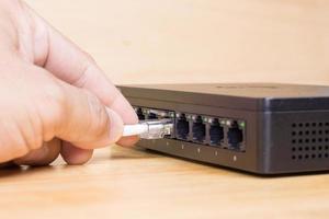 mano del hombre que sostiene los cables de red para conectar el puerto lan, tecnología de conexión de comunicación conceptual foto