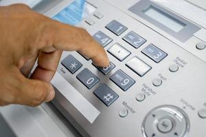 hand man está usando una máquina de fax en la oficina, equipo para transmisión de datos. foto