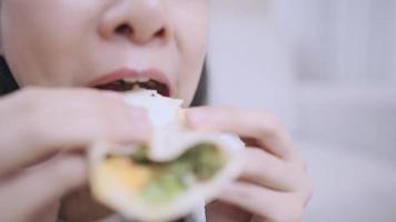 Young female worker quickly eating a sandwich for breakfast at office, close up mouth eating chewing shot, delicious food biting, happiness starts a day, alternative healthy food, vegetarian fiber eat video
