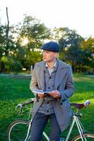 joven hipster masculino lee un libro en el parque de otoño foto